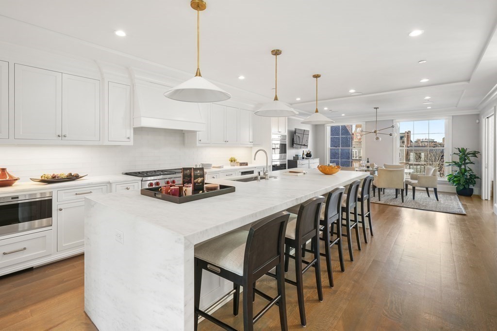 75 Beacon Street, Unit 2 Boston, MA 02108 - Photo 6 of 37 a kitchen with stainless steel appliances a table chairs stove and white cabinets