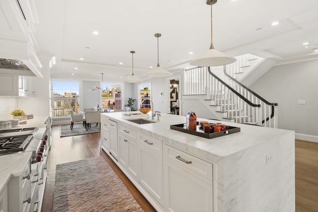a kitchen with sink stove and white cabinets with wooden floor