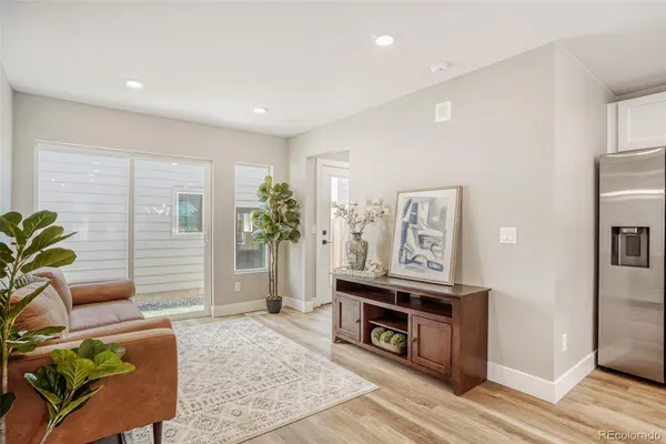 a living room with furniture kitchen view and a wooden floor