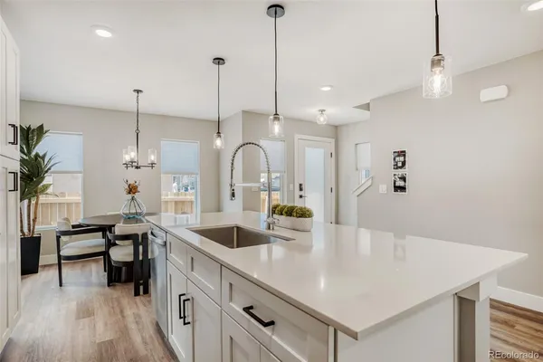 a kitchen with stainless steel appliances a sink a stove a refrigerator and island with wooden floor