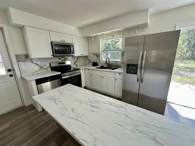 a kitchen with a refrigerator sink and wooden floor
