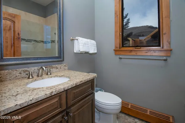 a bathroom with a granite countertop toilet sink and mirror