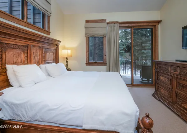a large white bed in a bedroom next to a window