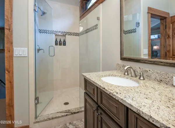 a bathroom with a granite countertop sink mirror and a shower