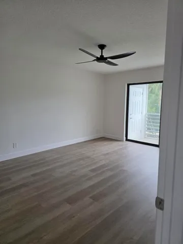 an empty room with wooden floor fan and windows