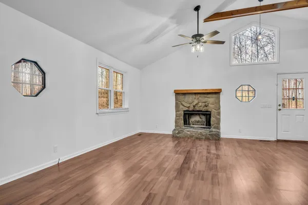 a view of an empty room with a window and wooden floor