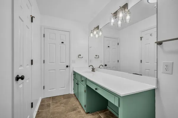 a bathroom with a sink a light fixture and a glass door