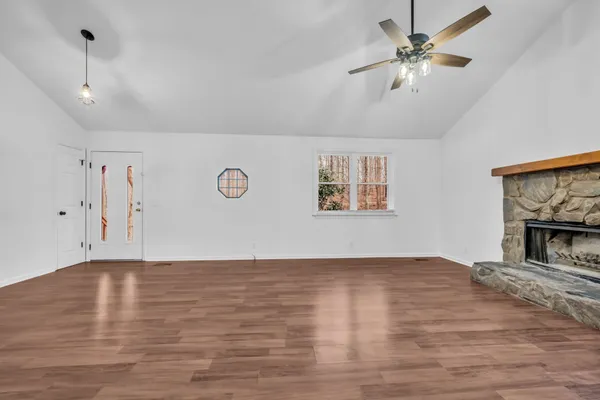 a view of an empty room with window and wooden floor