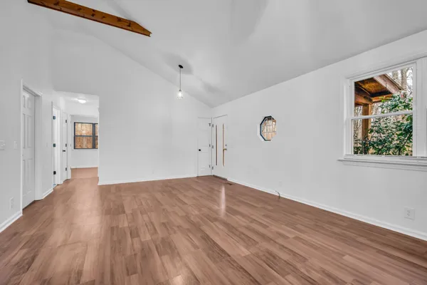 a view of an empty room with wooden floor and a window