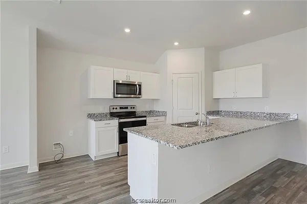 a kitchen with a sink a stove a microwave and wooden floor