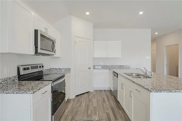 a kitchen with stainless steel appliances granite countertop a sink stove microwave and refrigerator