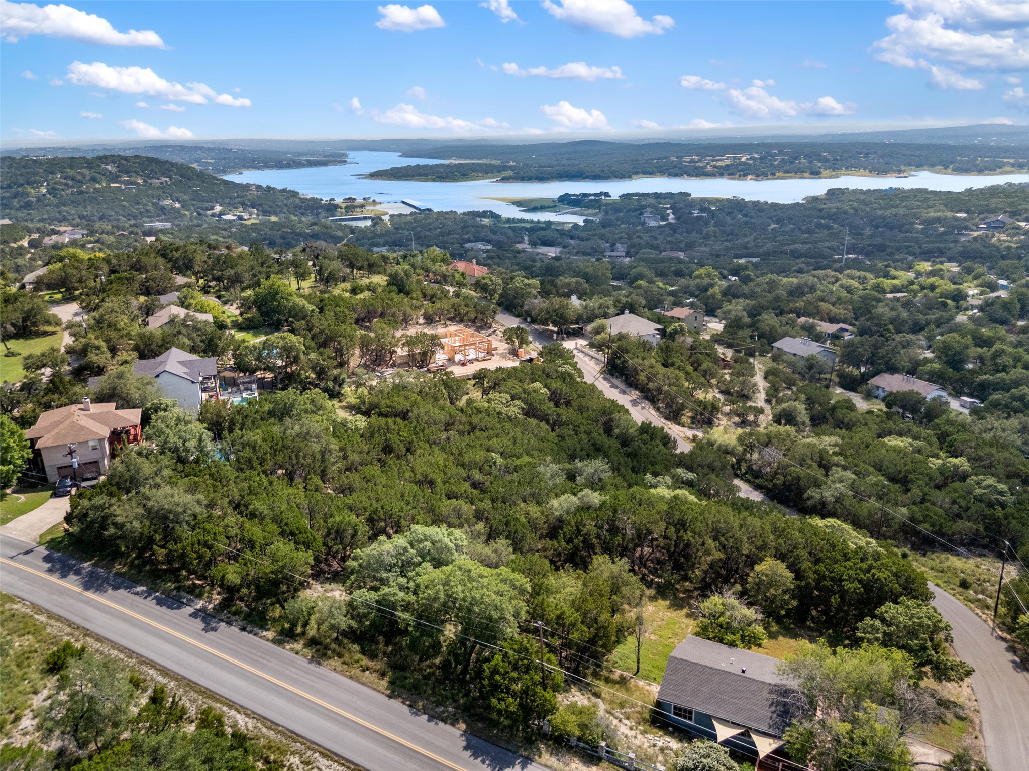 21105 Ridgeview Road Lago Vista, TX 78645 - Photo 5 of 34 A sweeping aerial view reveals a verdant landscape with scattered homes, a winding road, and a tranquil lake in the distance.