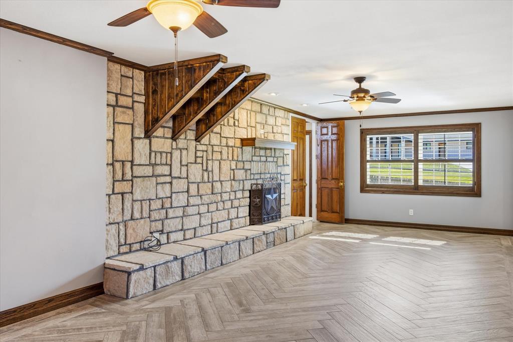424 Edwards Drive Dublin, TX 76446 - Photo 11 of 40 Unfurnished living room with ornamental molding, a ceiling fan, a wood burning fire place, and tile flooring in a Herringbone pattern