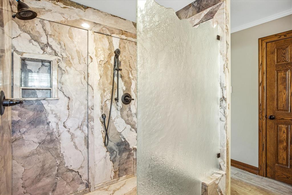 424 Edwards Drive Dublin, TX 76446 - Photo 22 of 40 Master bath featuring a large marble finish shower with decorative glass door and wood finished floors