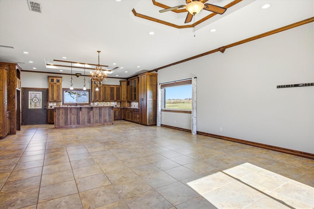 424 Edwards Drive Dublin, TX 76446 - Photo 5 of 40 Kitchen, Dining area, and LA featuring a tray ceiling, a kitchen island, ornamental molding, glass insert cabinets, and a chandelier
