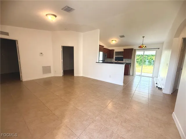 an empty room with kitchen view and wooden floor