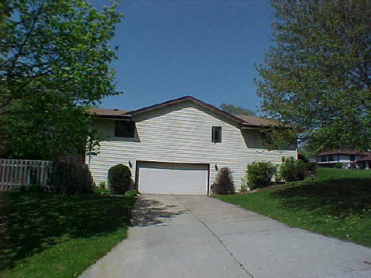 4613 Sunderman Road Rockford, IL 61114 - Photo 6 of 6 a view of a white house with a yard plants and large tree