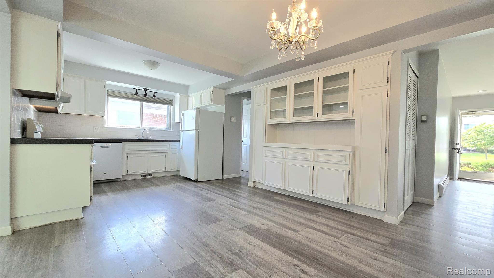 34294 Greentrees Road Sterling Heights, MI 48312 - Photo 13 of 20 Spacious kitchen featuring wood-finish flooring, white cabinetry, dark countertops, and a built-in display cabinet with glass-front uppers