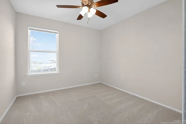 an empty room with a window and a fan