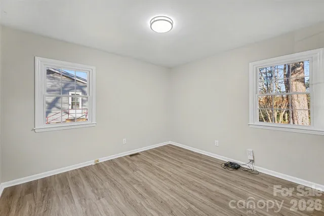 a view of empty room with window and wooden floor