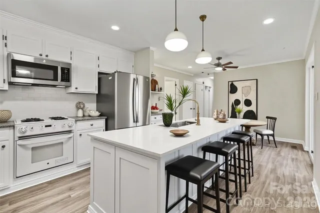 a open kitchen with stainless steel appliances kitchen island a table chairs and a refrigerator