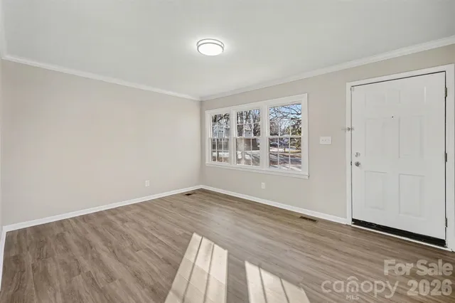 an empty room with wooden floor closet and windows