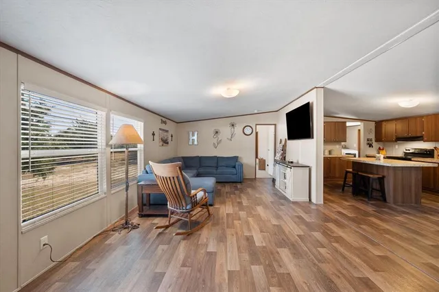 a living room with furniture a kitchen view and a wooden floor