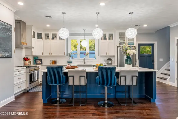 a kitchen with stainless steel appliances kitchen island granite countertop a table chairs and a refrigerator