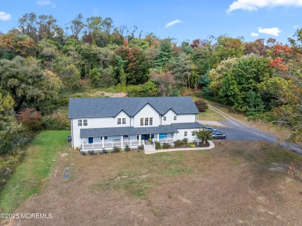an aerial view of a house with yard and trees in the background
