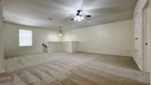 an empty room with chandelier fan and windows