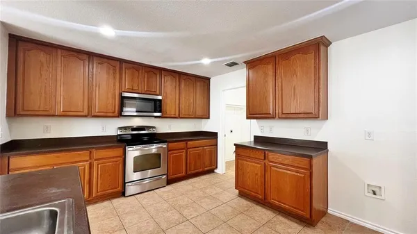 a kitchen with stainless steel appliances granite countertop wooden cabinets a stove top oven a sink and dishwasher
