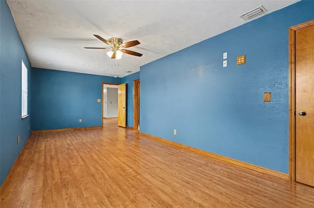 a view of an empty room with window and wooden floor