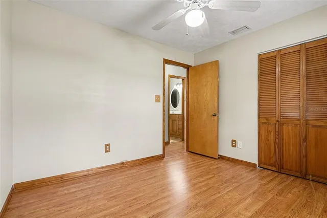 an empty room with wooden floor and ceiling fan