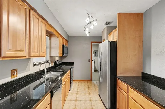 a kitchen with stainless steel appliances granite countertop a refrigerator a sink dishwasher a stove and white countertops with wooden floor