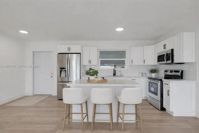 a kitchen with stainless steel appliances a dining table chairs microwave and sink