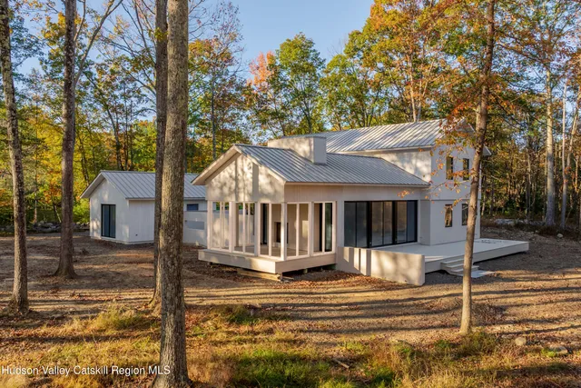 a view of a white house with large trees and wooden fence