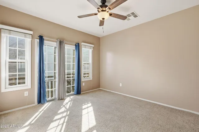 an empty room with windows and ceiling fan