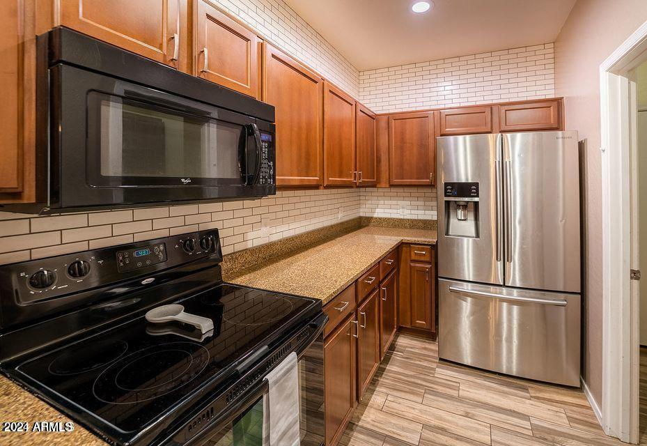 4757 East Waterman Street, Unit 103 Gilbert, AZ 85297 - Photo 9 of 27 a kitchen with wooden cabinets and stainless steel appliances