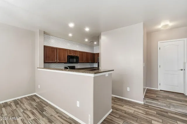 a view of kitchen and empty room with wooden floor