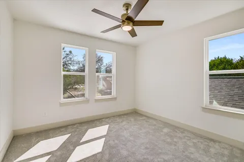 an empty room with windows and fan