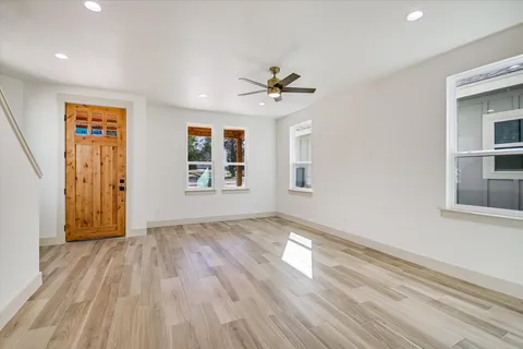 a view of empty room with wooden floor and fan
