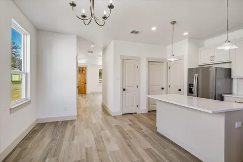 a large white kitchen with a refrigerator a sink stainless steel appliances and cabinets