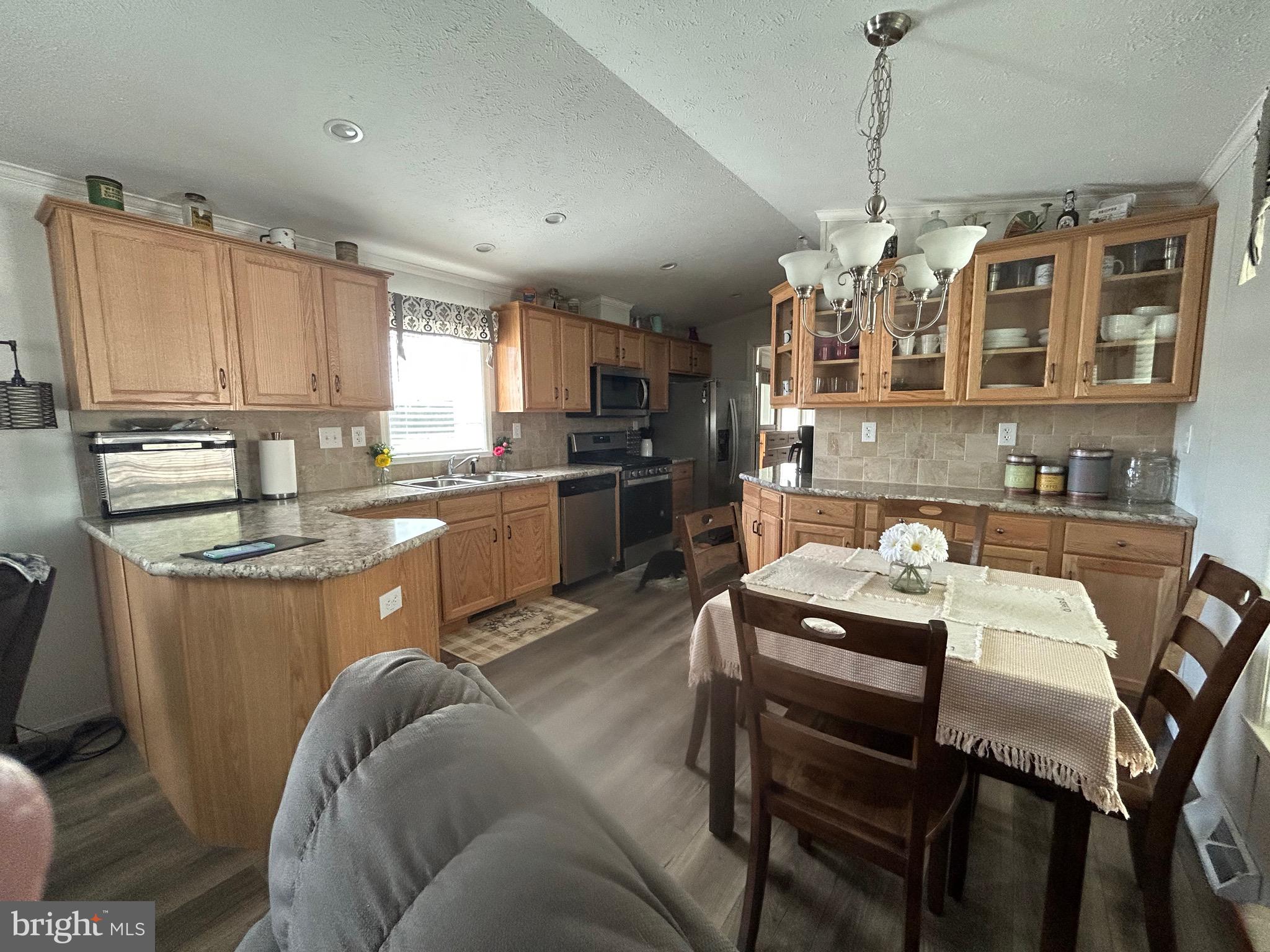 18 Jade Drive Lititz, PA 17543 - Photo 32 of 39 a kitchen with stainless steel appliances granite countertop a stove top oven a refrigerator a sink dishwasher a dining table and chairs with wooden floor