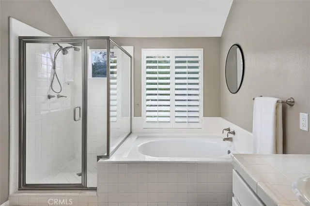 a bathroom with a tub a mirror and a shower