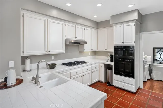 a kitchen with granite countertop a stove a sink and a refrigerator