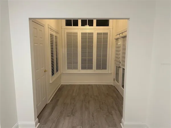 a view of an empty room with wooden floor and a window