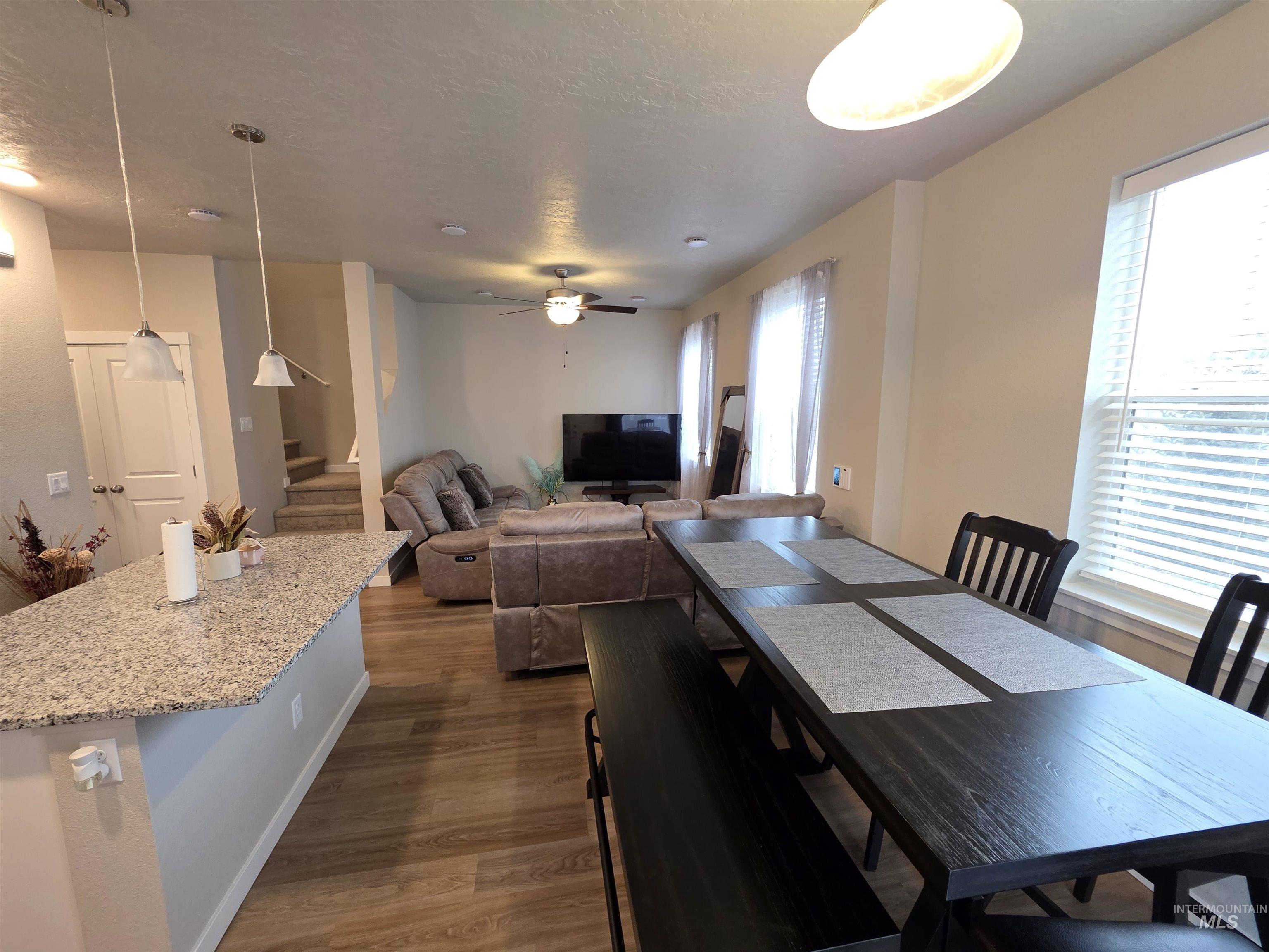 2316 East Spice Loop, Unit 4 Nampa, ID 83687 - Photo 2 of 12 Dining area featuring stairway, dark wood-style floors, ceiling fan, and a textured ceiling