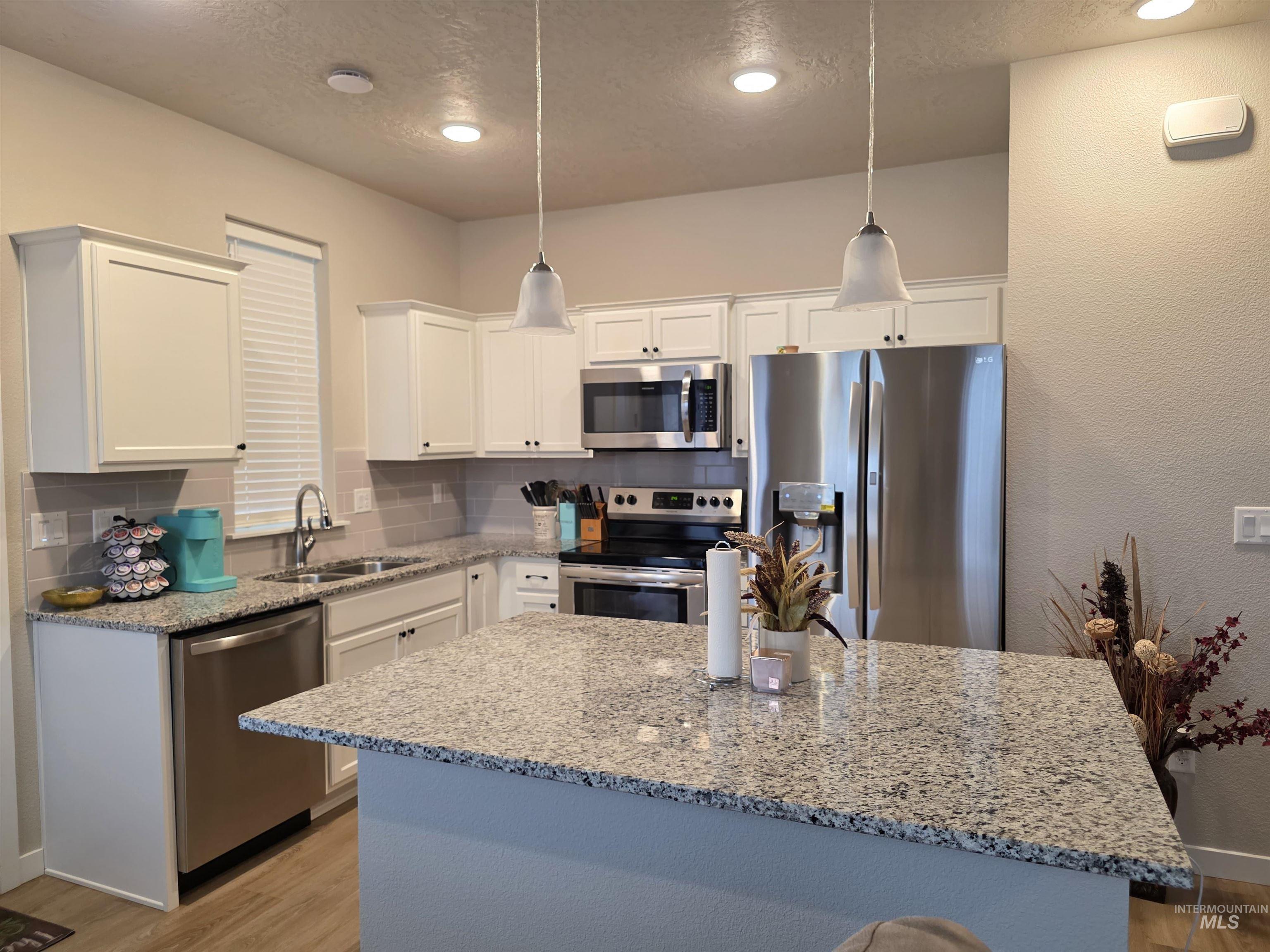 2316 East Spice Loop, Unit 4 Nampa, ID 83687 - Photo 3 of 12 Kitchen featuring stainless steel appliances, light stone countertops, pendant lighting, decorative backsplash, and recessed lighting