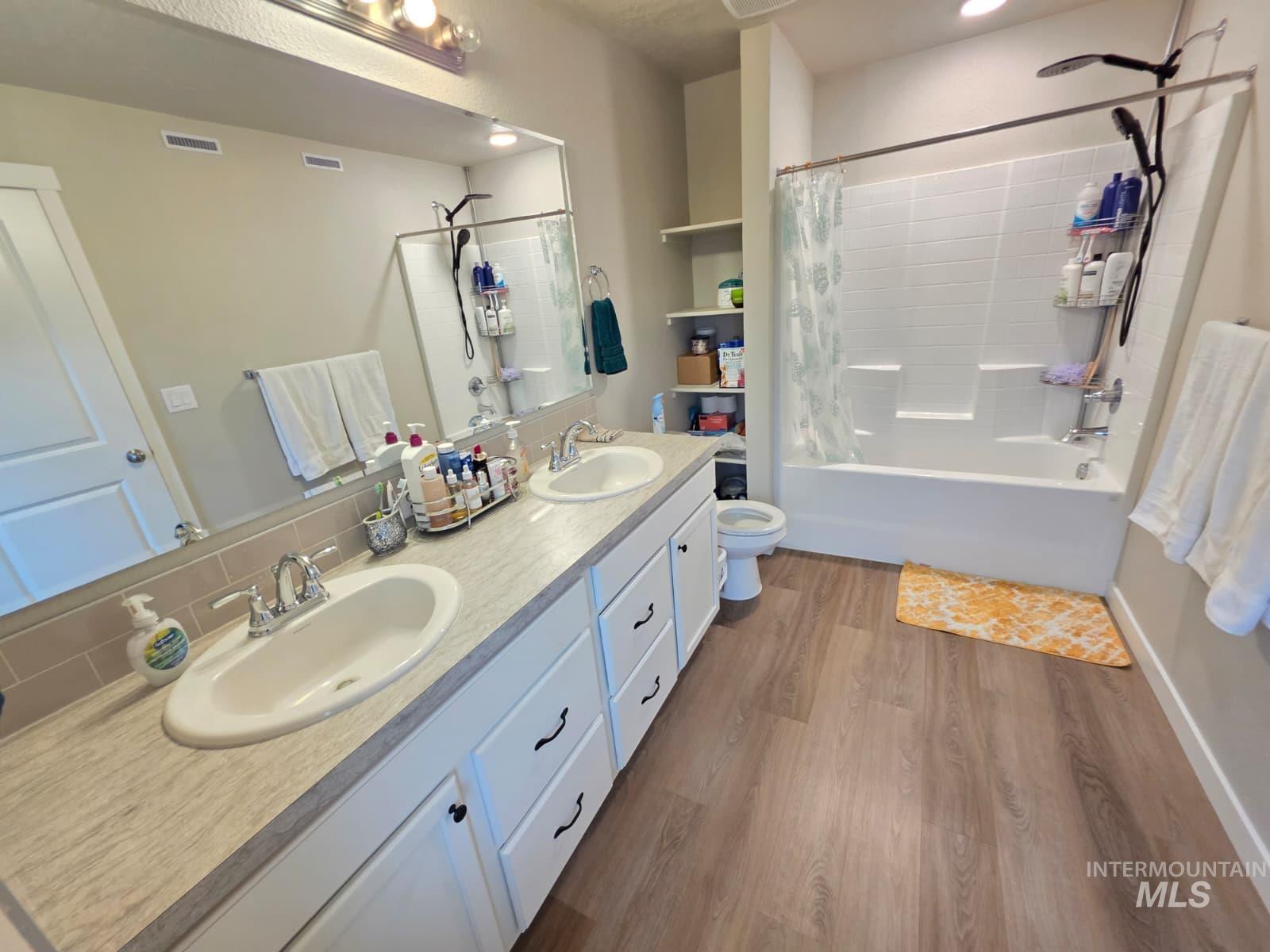 2316 East Spice Loop, Unit 4 Nampa, ID 83687 - Photo 7 of 12 Full bathroom featuring double vanity, dark wood finished floors, shower / tub combo with curtain, and decorative backsplash