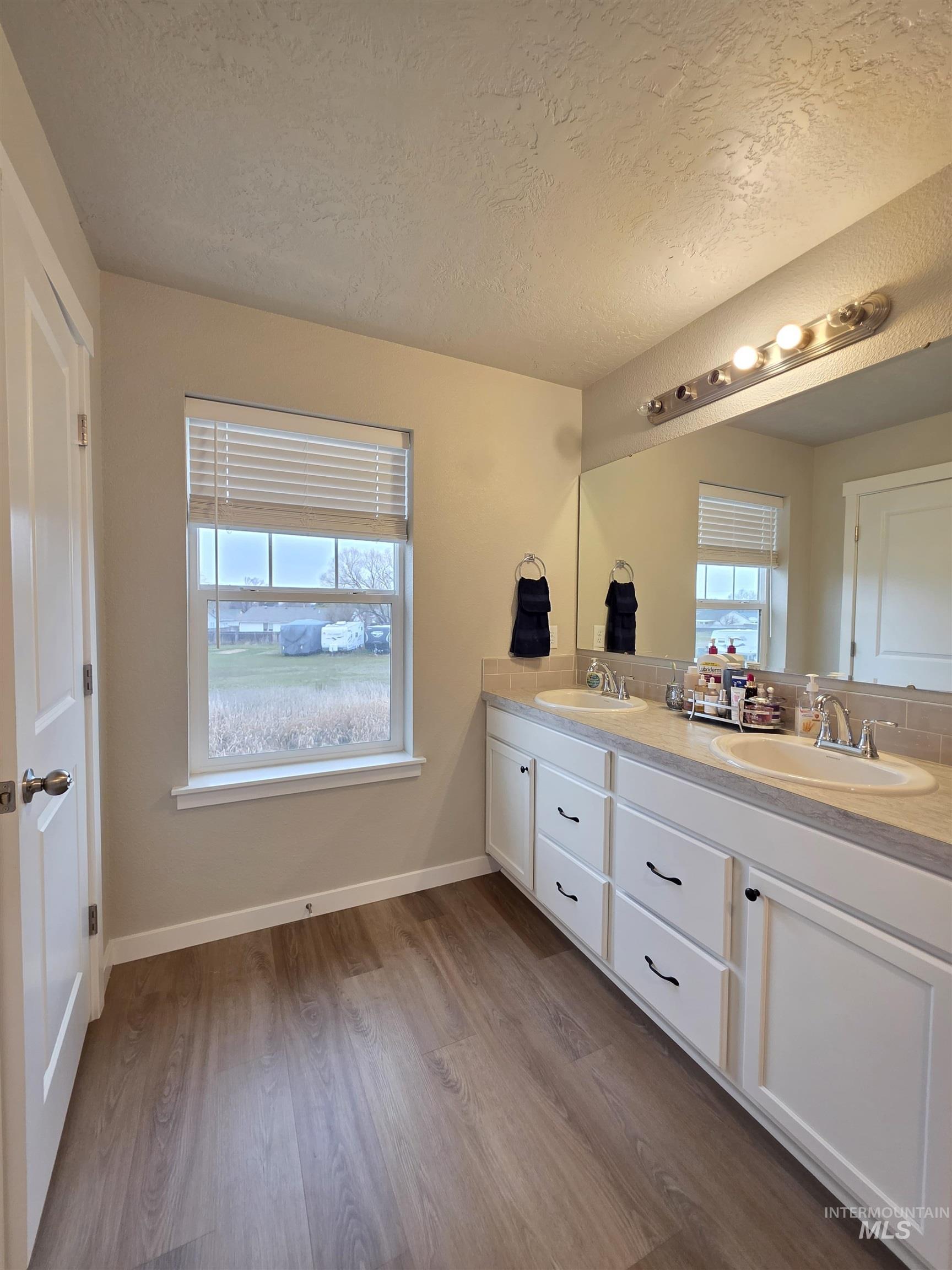 2316 East Spice Loop, Unit 4 Nampa, ID 83687 - Photo 8 of 12 Bathroom featuring double vanity, dark wood-style floors, and a textured ceiling